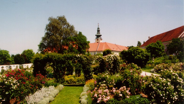 Historischer Hofgarten Stift Seitenstetten, © Gemeinde Seitenstetten Historischer Garten mit Blumen und Bäumen, im Hintergrund ein Gebäude mit Turm.