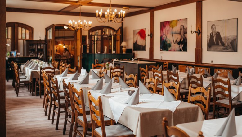 Gemütlich: Bunte Tiffany-Fenster und Holzlamperie, © Niederösterreich Werbung/Daniela Führer Ein gemütlicher Speisesaal mit Holzmöbeln, gedeckten Tischen und Kronleuchtern.