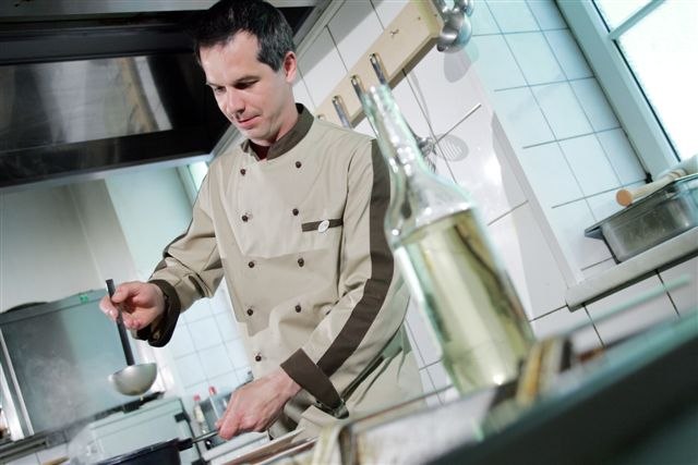 Gasthaus Graf, © weinfranz.at Ein Koch in einer professionellen Küche schöpft mit einer Kelle aus einem Topf.