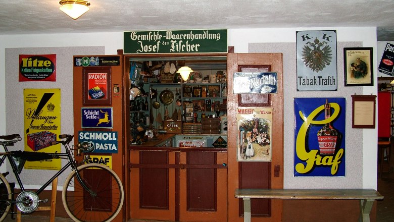 Historischer Laden im Mostviertler Bauernmuseum mit alten Werbeschildern und einem Fahrrad.