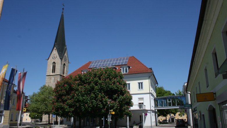Kirchturm und Gebäude in St. Valentin mit blauem Himmel.