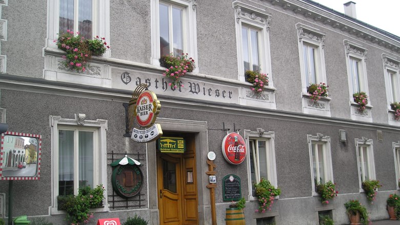 Fassade des Gasthofs Wieser mit Blumenkästen und Werbeschildern.