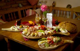 Ein Tisch mit einer Heurigenjause: Aufschnitt, K&auml;se, Brot und Wein.
