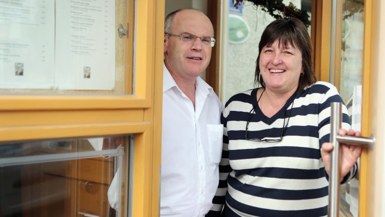 Ein Mann und eine Frau stehen l&auml;chelnd in einer T&uuml;r&ouml;ffnung eines Geb&auml;udes.