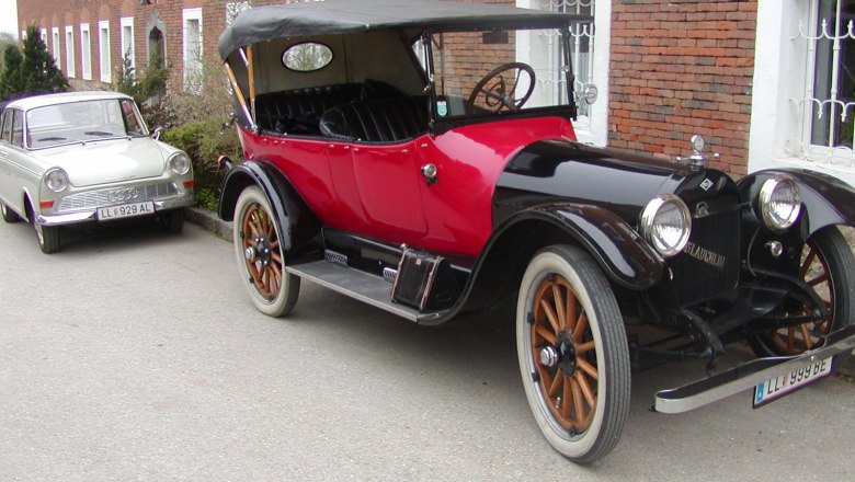 Zwei Oldtimer-Autos vor einem Backsteingebäude geparkt.