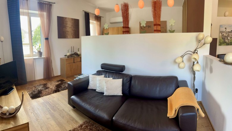 Modern eingerichtetes Wohnzimmer mit Ledersofa, Stehlampe und dekorativen Elementen.