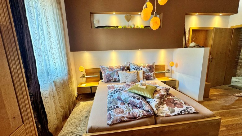 Gem&uuml;tliches Schlafzimmer mit Doppelbett, dekorativen Kissen und warmem Licht, das durch die Strau&szlig;eneierlampen den Raum erf&uuml;llt.