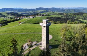 Aussichtsturm inmitten gr&uuml;ner H&uuml;gellandschaft.