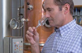 Mann riecht an einem Glas in einer Destillerie.