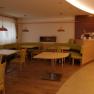 Innenansicht eines Cafés mit grünen Sitzbänken und Holztischen.