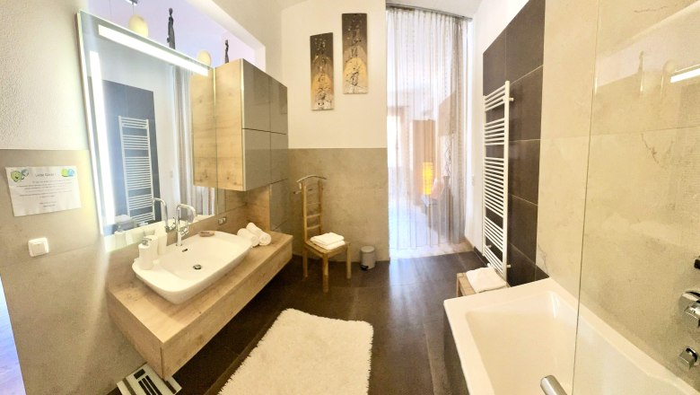 Modernes Badezimmer mit Badewanne, Waschbecken und gro&szlig;em Spiegel.
