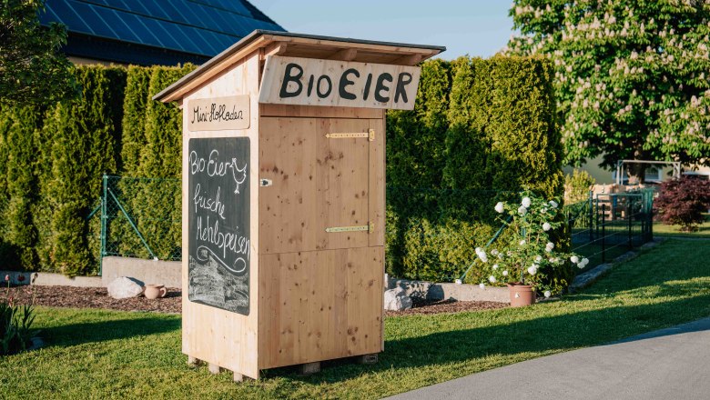Bio Eier und frische Mehlspeisen werden auf einem Schild angepriesen, das vor dem kleinen Holzhofladen direkt vor dem Wieserhof angebracht ist