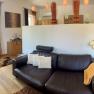Modern eingerichtetes Wohnzimmer mit Ledersofa, Stehlampe und dekorativen Elementen.