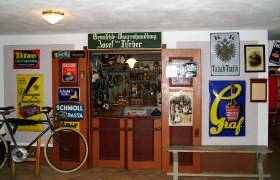 Historischer Laden im Mostviertler Bauernmuseum mit alten Werbeschildern und einem Fahrrad.