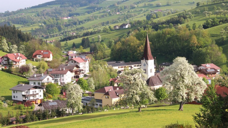 Ländliche Landschaft mit Kirche und blühenden Bäumen.