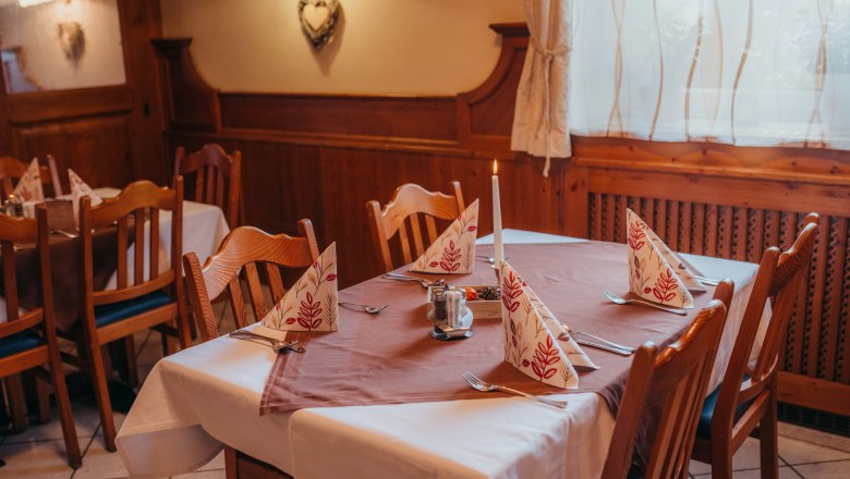 Gem&uuml;tlich gedeckter Tisch in einem rustikalen Restaurant mit Holzverkleidung.