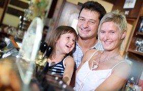 Eine lächelnde Familie steht in einem Restaurant oder Hotel an der Bar.